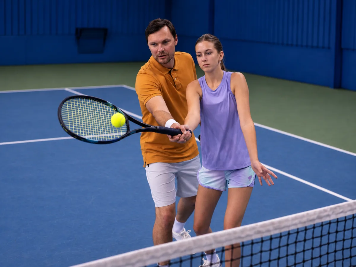Tennis coach helping a player practice a volley